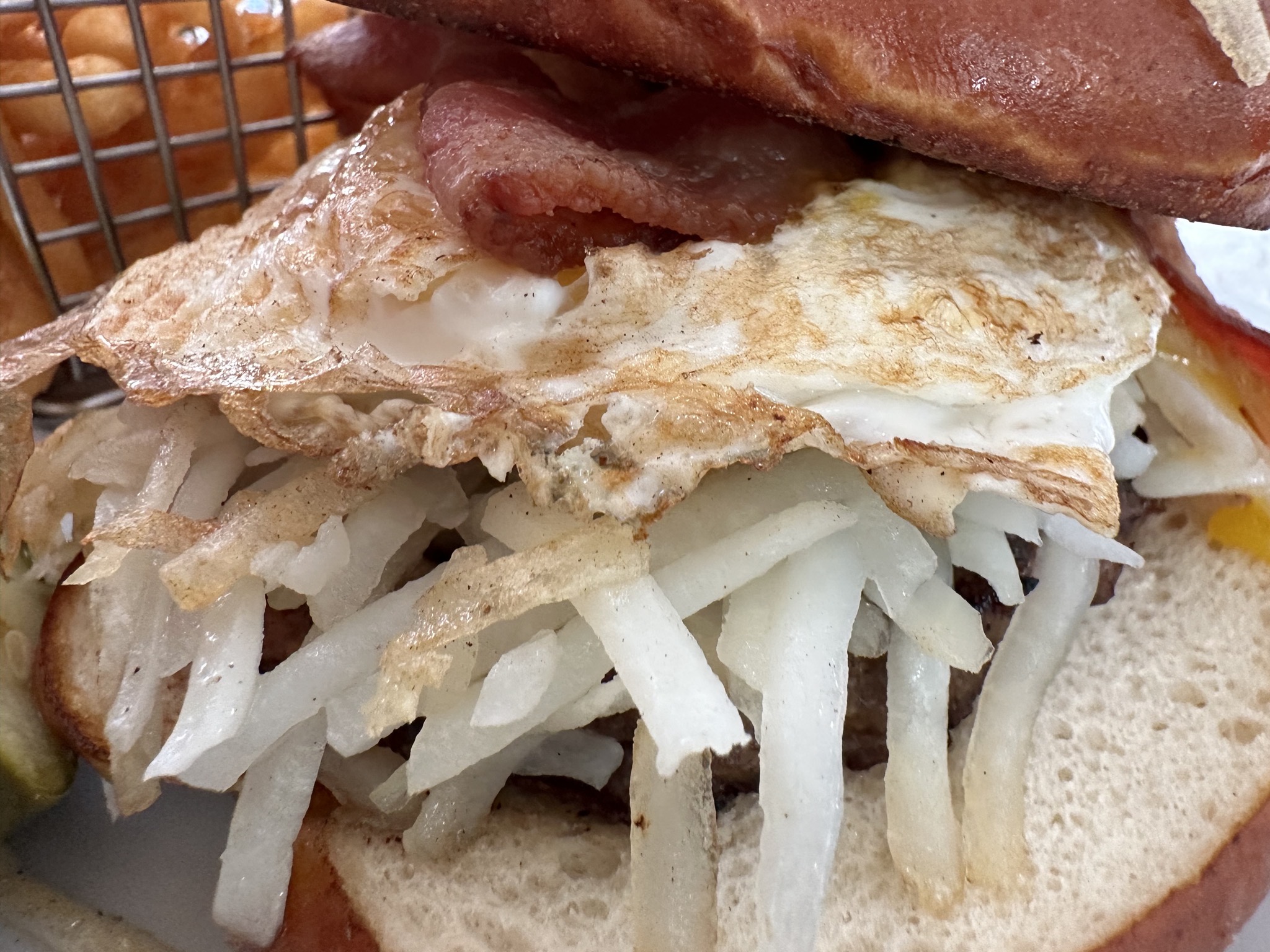 Fries and burger with bacon, egg, hash browns