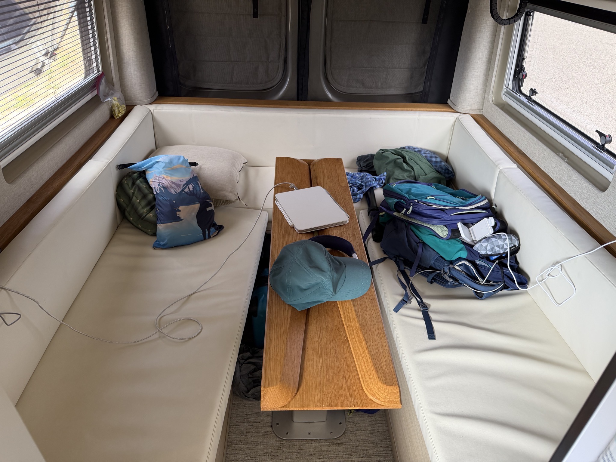 U-shaped lounge below the lift bed, with height-adjustable table; the sides can fold in for easier access